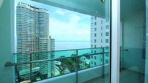 A high-rise building with a glass balcony overlooking a body of water. - StayNest Suites at Gurney Drive (George Town)