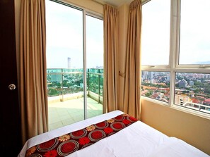 A hotel room with a bed, large windows, and a view of a cityscape. - StayNest Suites at Gurney Drive (George Town)