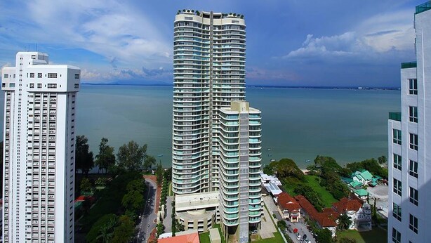 A high-rise hotel with multiple balconies, a view of the sea, and surrounding greenery. - StayNest Suites at Gurney Drive (George Town)