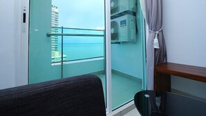 A balcony with a glass door, a view of the sea, and a fan on the wall. - StayNest Suites at Gurney Drive (George Town)