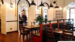 A restaurant with wooden tables and chairs, hanging pendant lights, and framed pictures on the walls. - StayNest Suites at Gurney Drive (George Town)