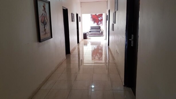 A hallway with tiled flooring, framed artwork on the walls, and a staircase at the end. - Eddy Vic Hotel (Abuja)