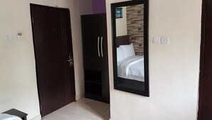 A bedroom with a bed, a wardrobe, and a mirror reflecting a bed. - Eddy Vic Hotel (Abuja)