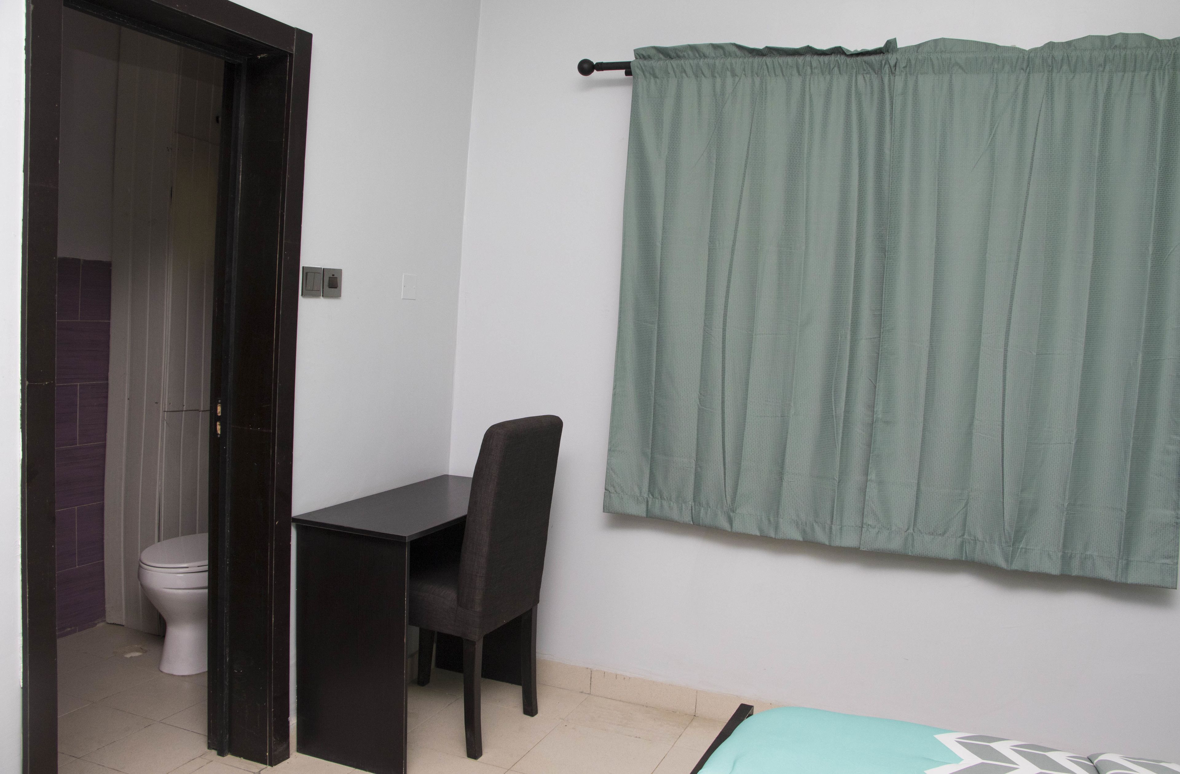 Una habitación pequeña con escritorio, silla y retrete.