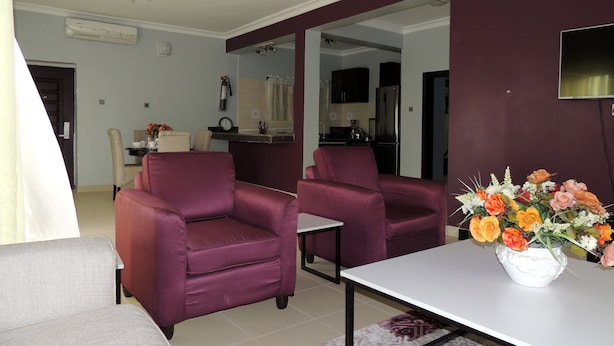 Een woonkamer met twee paarse fauteuils, een witte salontafel en een bloemenvaas.