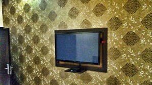 A television mounted on a patterned wall. - The 09 Suites (Abuja)