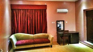 A living room with a sofa, a small table, and an air conditioning unit on the wall. - The 09 Suites (Abuja)