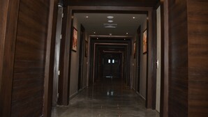 A long, narrow hallway with wooden walls and a polished floor, leading to a darkened area at the end. - Hide Away Suites (Noida)