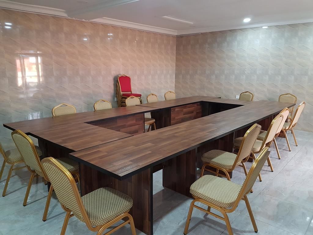 A conference room with a long wooden table, wicker chairs, and a red chair.