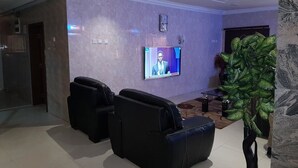 Un hall d’entrée avec un espace salon, un écran de télévision et une plante.