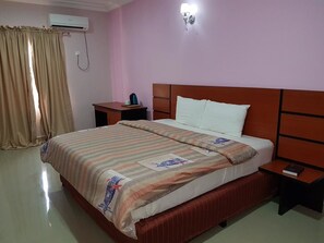 A bedroom with a bed, a nightstand, a lamp, and an air conditioning unit. - De George's Grand Resort (Karu)