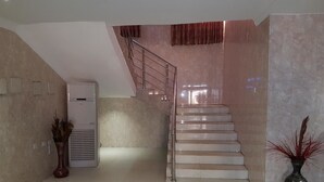 Un escalier avec une rampe en métal menant à un palier, un climatiseur fixé au mur et une plante en pot.