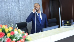 A hotel reception area with a reception desk, a telephone, and a sign indicating the reception. - Berlottue Hotel (Addis Ababa)