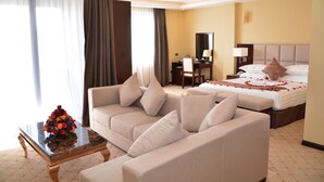 A hotel room with a sofa, a bed, a desk, and a mirror. - Berlottue Hotel (Addis Ababa)