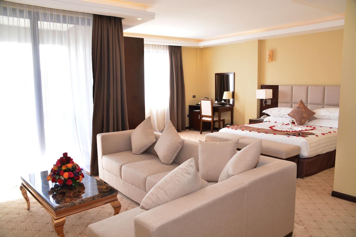 Une chambre d’hôtel avec un canapé, un lit, un bureau et un miroir.