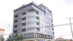 A multi-story hotel with balconies, a sign indicating it is a hotel, and visible power lines. - Berlottue Hotel (Addis Ababa)