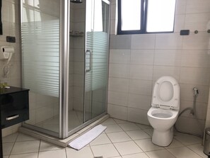 Un ba ño moderno con ducha envuelta en vidrio, inodoro y lavamanos con toallero.