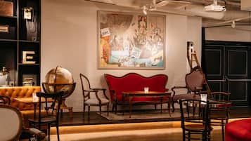 A room with a red sofa, wooden chairs, a globe, and a framed artwork on the wall.