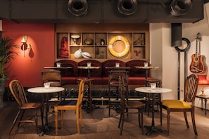 A cozy bar area with wooden furniture, a red wall, and various decorative items. - Ruby Lissi Hotel Vienna by IHG (Vienna)