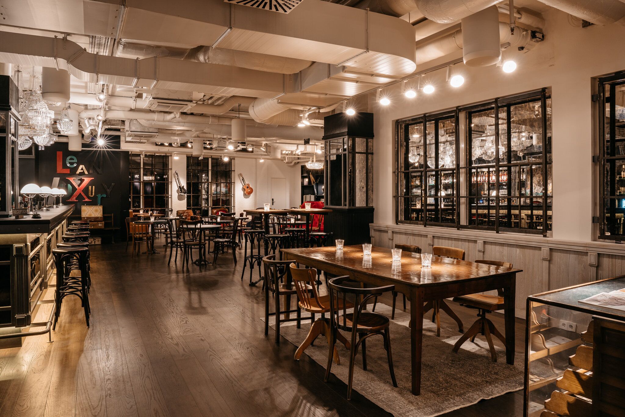 A spacious restaurant with high ceilings, exposed ductwork, and a variety of seating arrangements including tables and bar stools.
