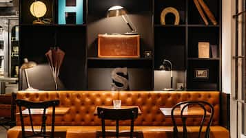 A cozy, well-lit seating area with a leather booth, two wooden chairs, and a table with a glass.