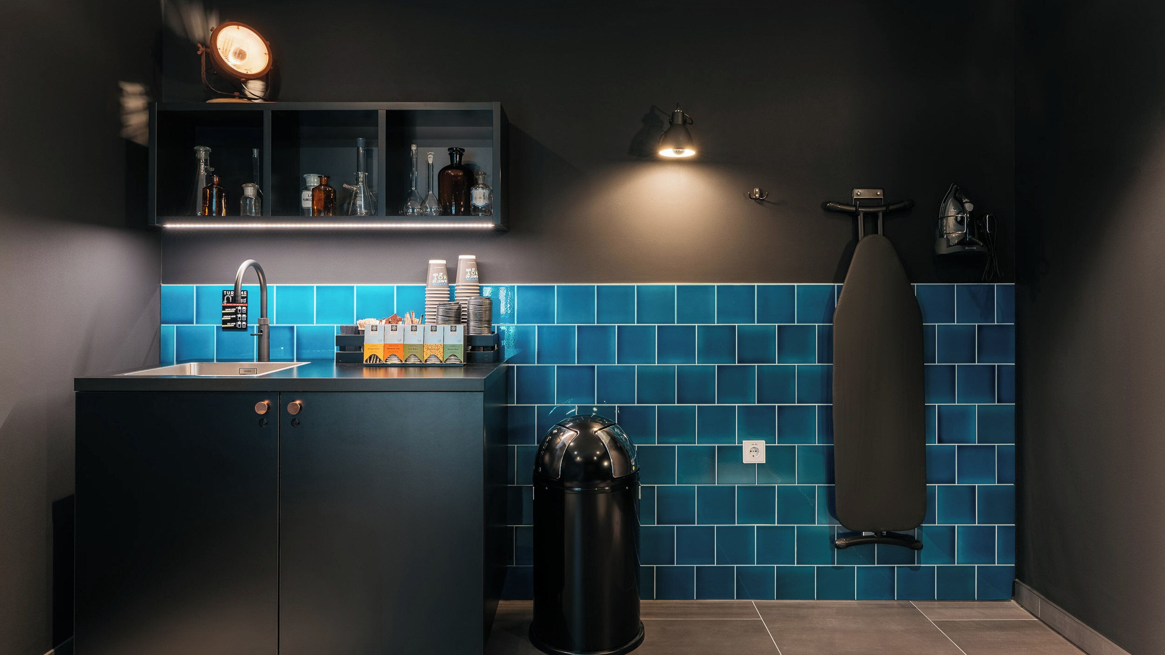 A modern bathroom with a dark cabinet, a sink, and a blue-tiled wall.