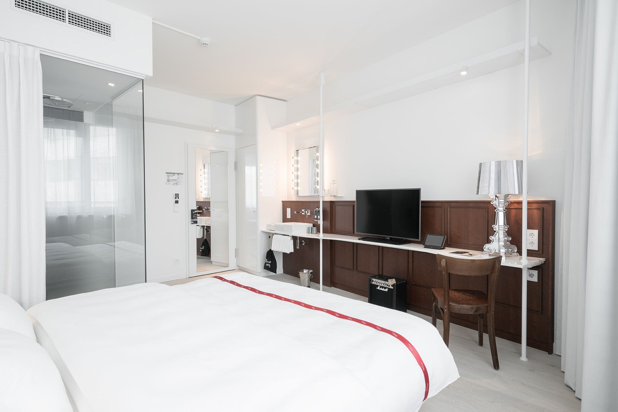 Een moderne hotelkamer met een groot bed, een bureau met computer, een televisie en een kaptafel met spiegels.