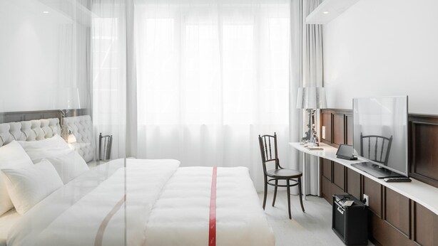 Una habitación de hotel moderna con una cama grande, un escritorio con una computadora portátil, una silla y un televisor.