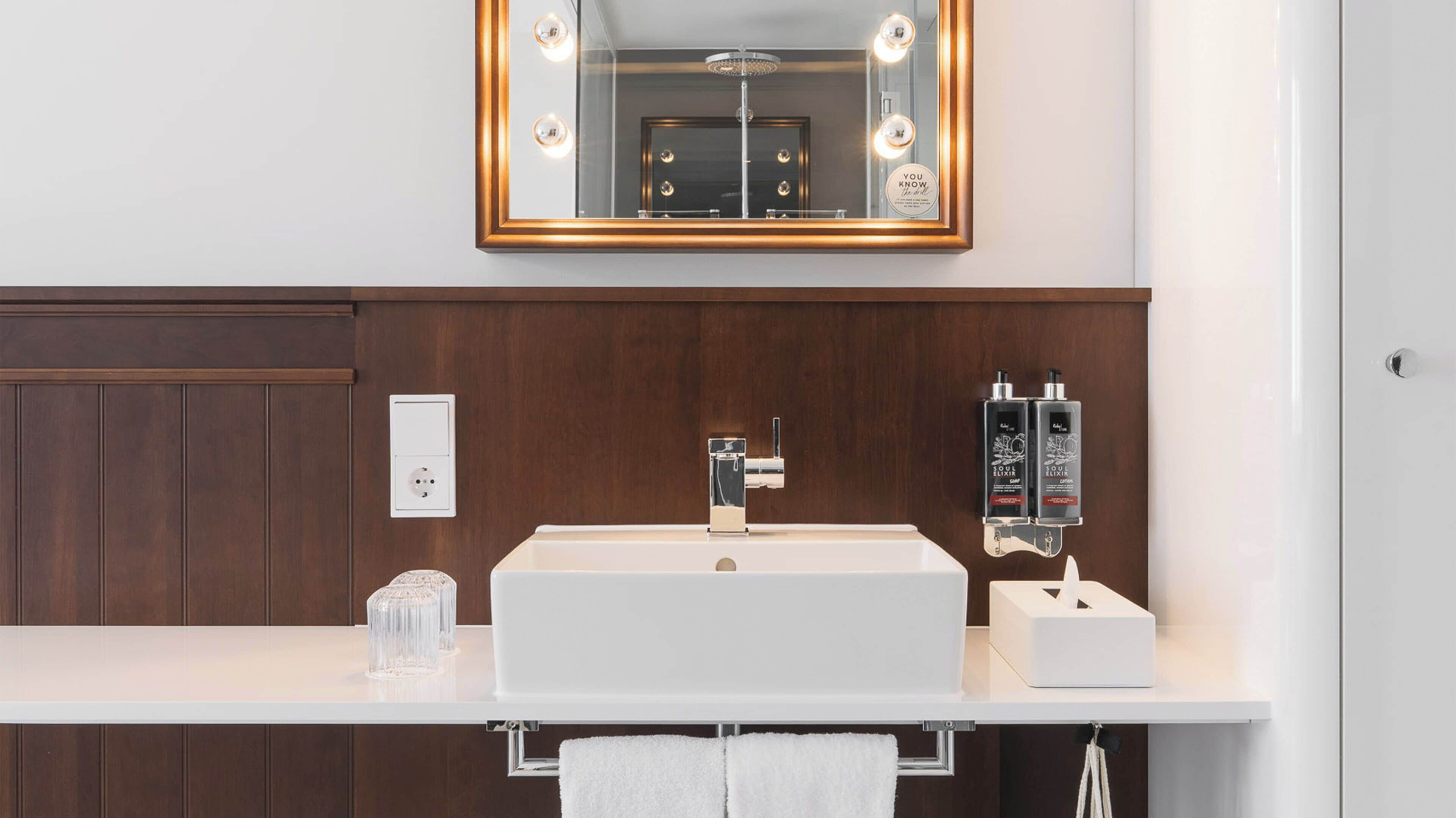 Ein modernes Badezimmer mit großem Spiegel, Waschtisch und zwei Lotionflaschen.