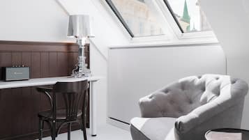 Una habitación moderna con techo alto, tragaluz, zona de bar con lámpara y sillón capitonado.