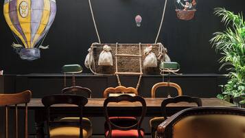 A dining area with a high table and chairs, a wicker basket with bags, and a wall mural with a hot air balloon.