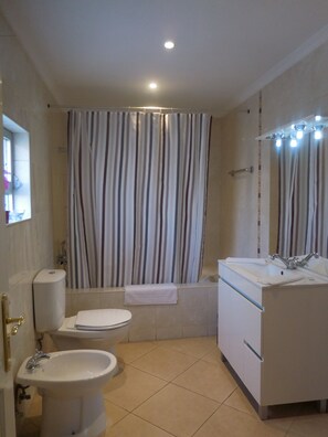 Ein Badezimmer mit Toilette, Bidet, Waschbecken und Duschvorhang.