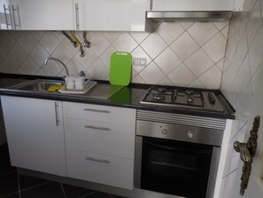 Apartamento, 2 quartos | Cozinha americana privada | Geladeira, micro-ondas, fogão, cooktop