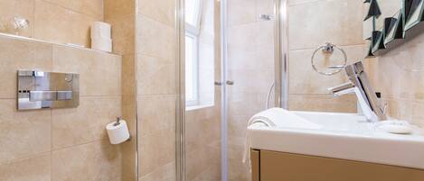 Un bagno moderno con box doccia in vetro, lavandino bianco e water.