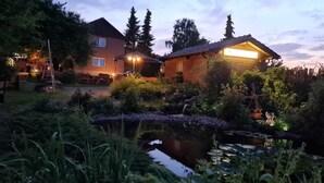Ein Haus mit Teich, umgeben von üppigem Grün und Bäumen.