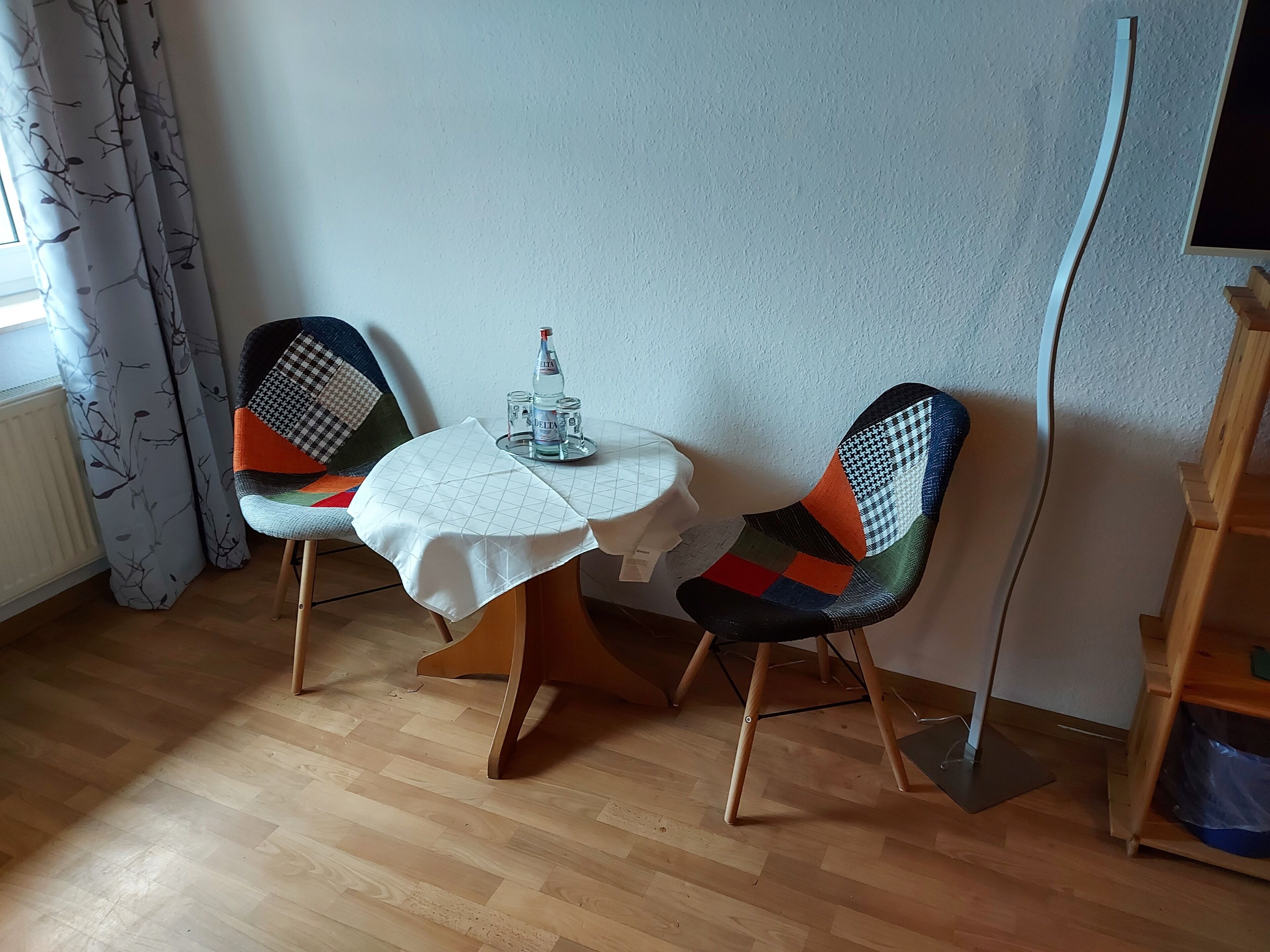 Ein kleiner Essbereich mit einem runden Tisch, zwei Stühlen, einer Wasserflasche und einem Glas.