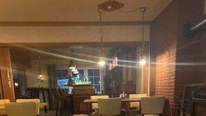Ein Essbereich mit Holztischen und -stühlen, einer Ziegelwand und hängenden Lampen.