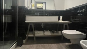 A modern bathroom with a glass shower enclosure, a white sink, and a white toilet. - Toledo Loft (Naples)
