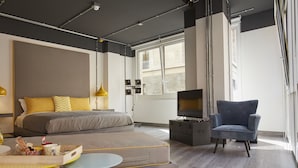 A modern bedroom with a bed, bedside table, TV, and a chair. - Toledo Loft (Naples)