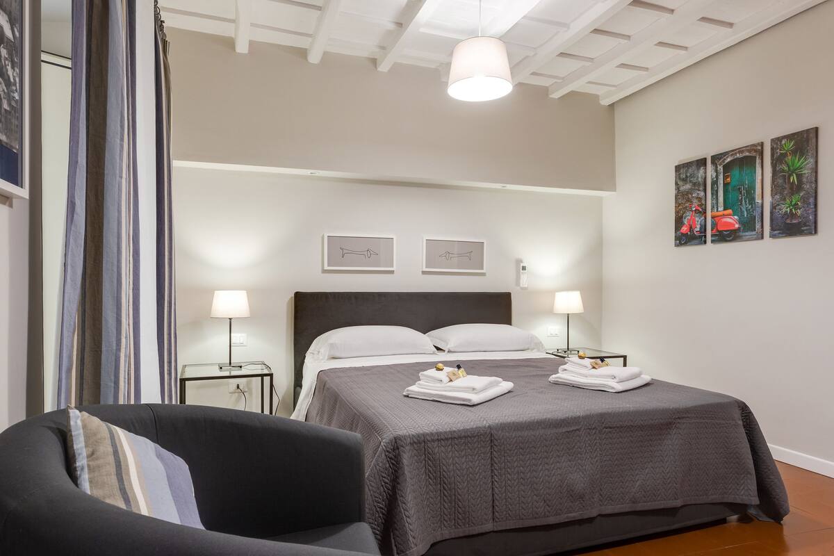 A neatly arranged bedroom with a bed, bedside tables, and a chair.