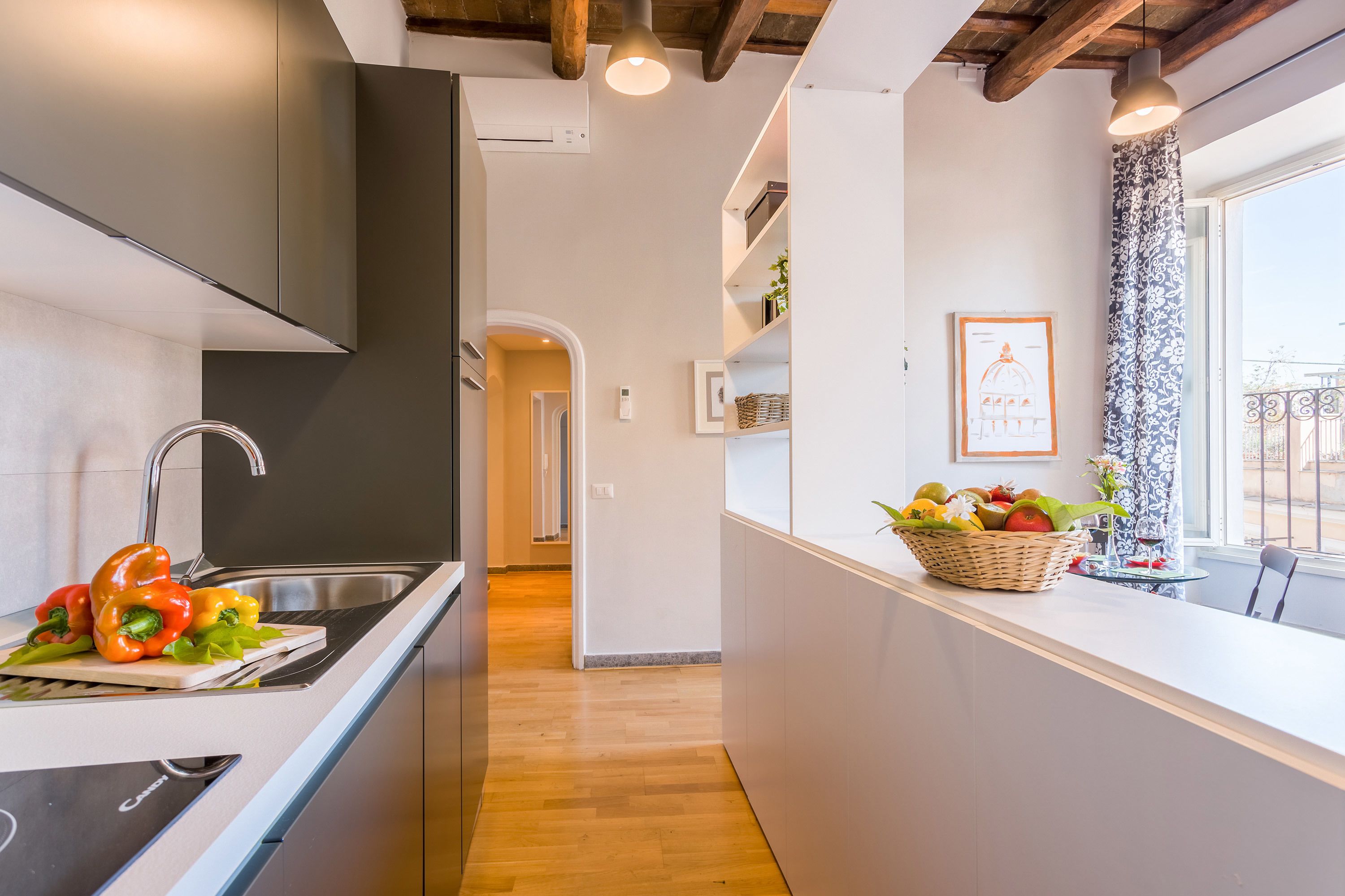 A modern kitchen with a wooden floor, a stainless steel sink, and a window with a view.