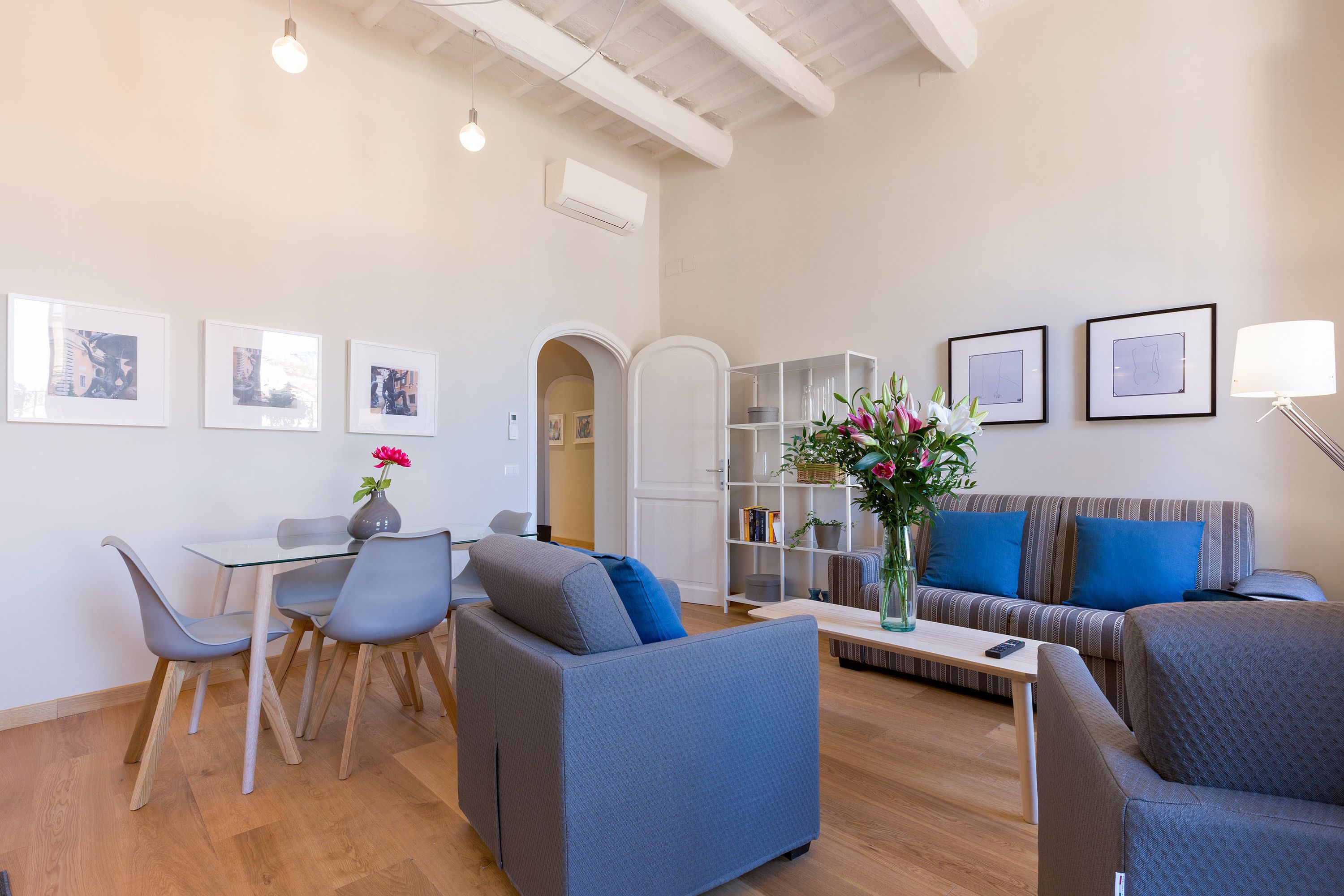 A modern living room with a sofa, chairs, a coffee table, and a dining area with a table and chairs.