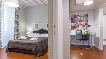 A modern bedroom with a large bed, a desk with a computer, and a wall art piece.