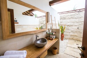 A bathroom with a stone sink, wooden vanity, and a large mirror.