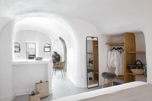 A modern bedroom with a large mirror, a wardrobe, and a seating area.