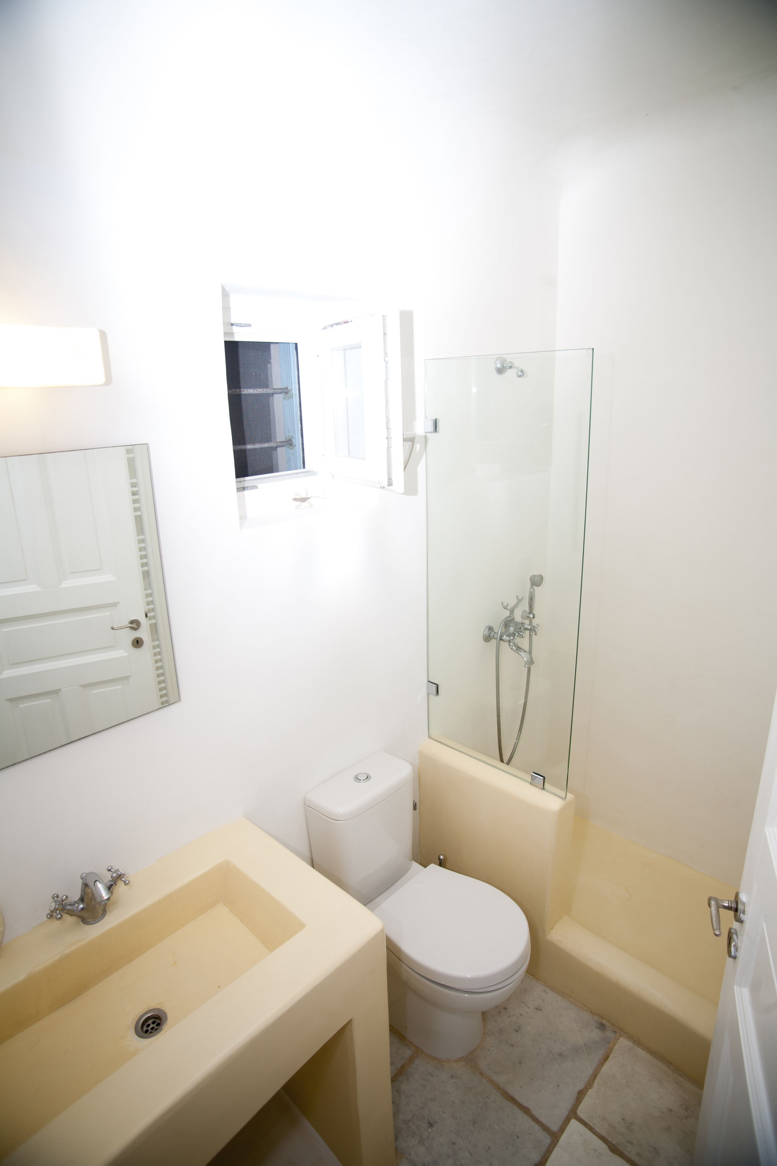 Un baño con lavamanos, inodoro y ducha con mampara de vidrio.