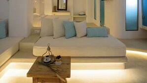 A modern living room with a sofa, a wooden coffee table, and a television mounted on the wall. - Mykonos Moussa Suites (Mykonos)