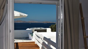 A balcony with a wooden floor, white railing, and a view of the sea and distant mountains. - Mykonos Moussa Suites (Mykonos)