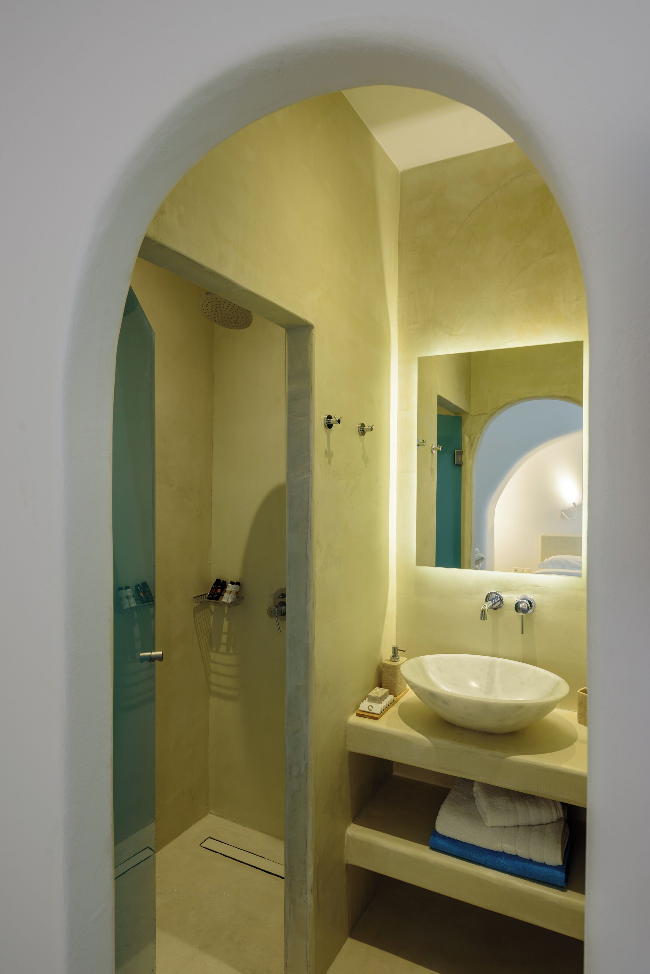 Un baño con lavamanos blanco, un espejo y zona de ducha.