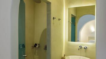 A bathroom with a white sink, a mirror, and a shower area.